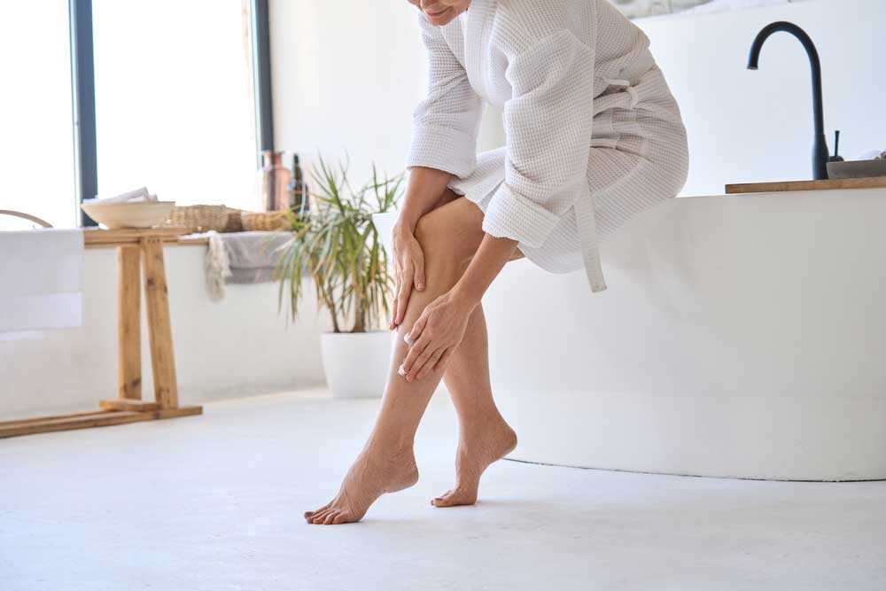 A woman is sitting on the floor with her feet on a towel